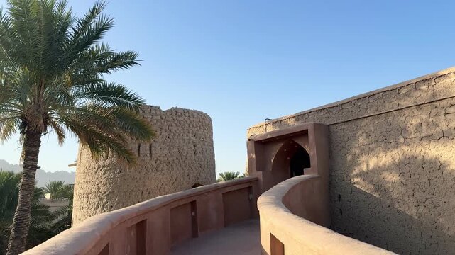Historic Al Aqr Wall in Nizwa showing traditional Omani architecture with mud buildings palm trees and old defensive structure in a famous cultural landmark. Nizwa, Oman - February 20, 2026