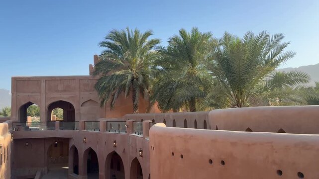 Historic Al Aqr Wall in Nizwa showing traditional Omani architecture with mud buildings palm trees and old defensive structure in a famous cultural landmark. Nizwa, Oman - February 20, 2026