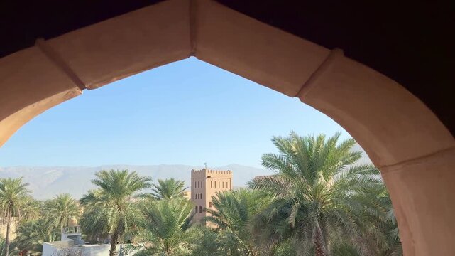 Historic Al Aqr Wall in Nizwa showing traditional Omani architecture with mud buildings palm trees and old defensive structure in a famous cultural landmark. Nizwa, Oman - February 20, 2026