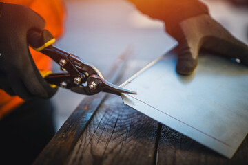 A man cuts a metal sheet with metal shears, construction work. Sheet metal shears snips cut edge of...