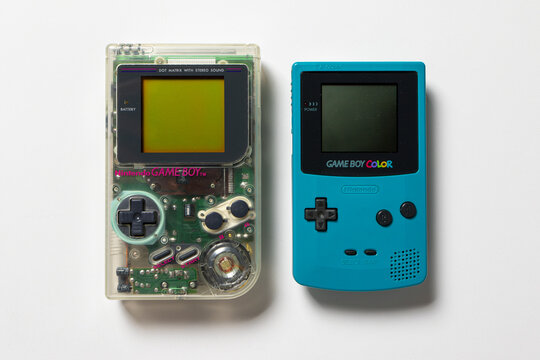 Two Nintendo Game Boy consoles. One is a transparent DMG Play It Loud and the other ir a teal Color.