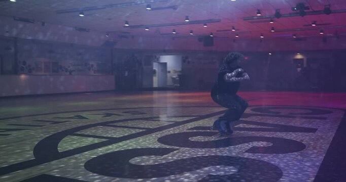 Beautiful, cinematic steady cam shot around silhouetted skater doing amazing spins under disco ball