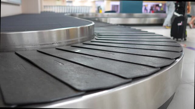Conveyor belt carousel spinning at airport terminal hall, luggage claim in arrival area, passengers awaiting for baggage transfer after flight in airport. Automatic moving line in destination area.