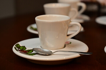 Obraz premium white ceramic coffee cups with saucers and spoons on wooden table, elegant espresso service at corporate event or wedding, hospitality setup with small coffee cups for guests, hot beverage station at 