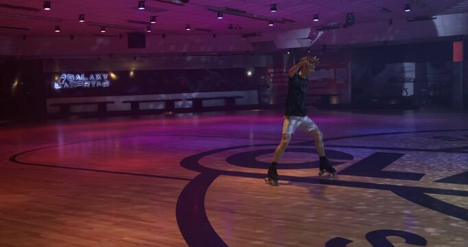 Skilled young skater doing long, one-legged spin underneath glowing disco ball