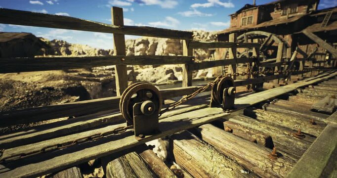 Rusting machinery and weathered wood dominate this abandoned mining site, nestled between towering rock formations under a clear blue sky. Nature reclaims its territory here.