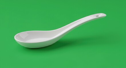 Minimalist studio shot of a white porcelain asian soup spoon with a green background showing
