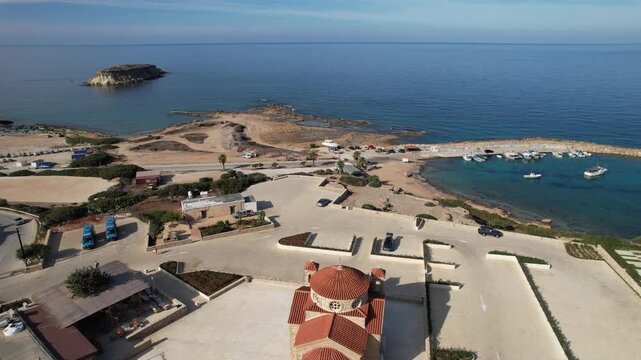 Drone aerial 4K resolution of Agios georgios church overlooking the mediterranean sea, a small harbor with boats. Geronisos island Peyia Paphos coastline cyprus