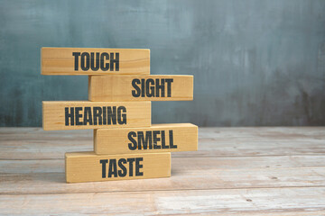 Five human senses concept with wooden blocks labeled touch, sight, hearing, smell and taste on...
