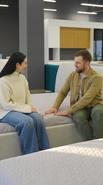 Happy couple testing orthopedic mattress in showroom