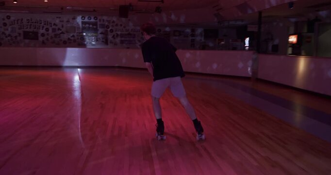 Young, experienced skater doing amazing tricks across colorful but empty dance floor - steady cam following