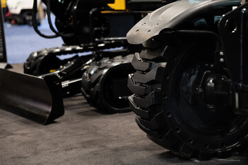 Close view of heavy equipment tire, blade, and tracked machine display at a trade show, suited for construction business and procurement use