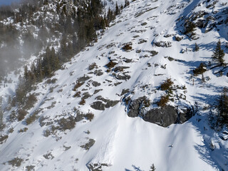Snow Covered Rocky Mountain Slope With Evergreen Trees and Shadowed Ridges in BC, Canada
