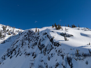 Snowy Mountain Ridge With Evergreen Trees Under Clear Blue Sky in BC, Canada