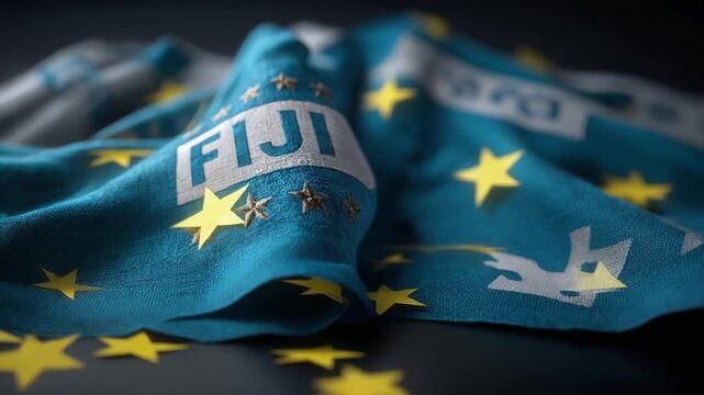 A close-up view of a flag with a deep blue background and yellow stars. The word FIJI is displayed