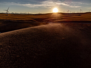 Energy production by windmills overlooking rolling hills at sunset producing green power in Alberta Canada.
