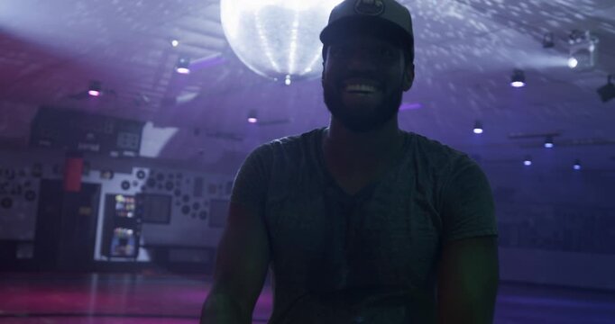 Silhouette of smiling skater on disco dance floor making fun hand gestures - medium steady cam shot