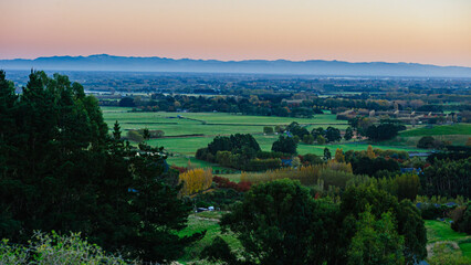 Fototapeta premium Golden Light Over Rolling Hills and Farmland Near Lake Tekapo, New Zealand 