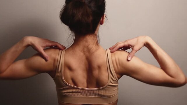 Sport body woman doing stretching exercises for shoulders, scapula and healthy back, fitness body lifestyle. Fit naked muscles model in studio with copy space. Back view.