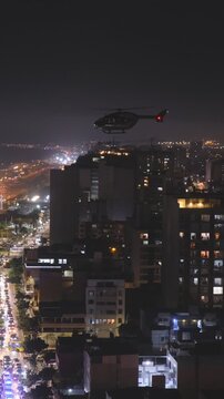 Aerial view of a city at night with a helicopter flying over buildings and heavy traffic below