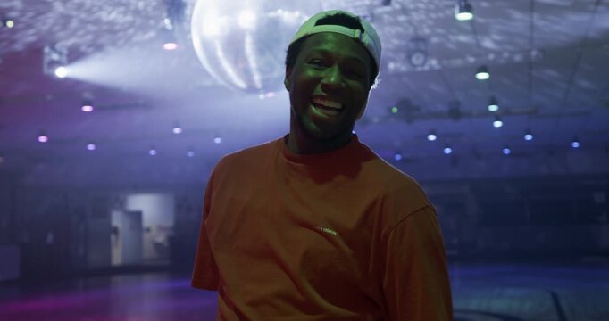 Epic, professional male skater doing awesome spin and posing in front of disco ball - medium shot