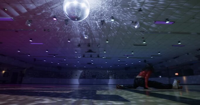 Beautiful female skater alone on disco floor doing awesome spin then sudden slits - wide shot