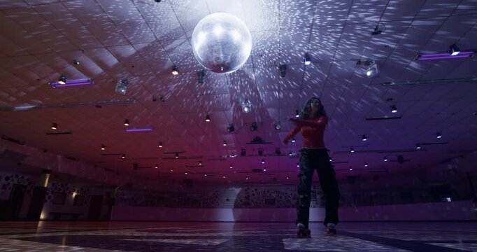 Impressive roller skater in disco room attempting spin move, failing and trying again 