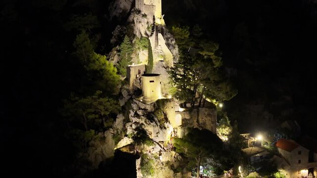 Mirabela tower illuminated above Omis old town during peaceful night on Adriatic coast.