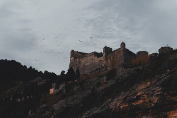 Fototapeta premium time Dramatic Medieval Castle on Cliff at Dusk, Cinque Terre Italy