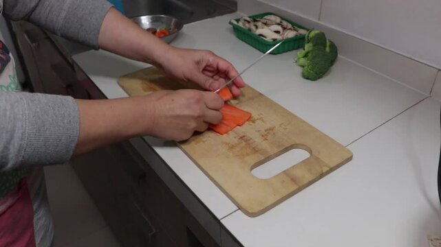 cortando zanahorias en juliana sobre una tabla de madera en la cocina