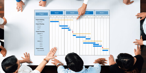 Obraz premium Team collaboration around a Gantt chart showcasing project management strategies and timelines, emphasizing effective planning and execution in an office environment. Amity