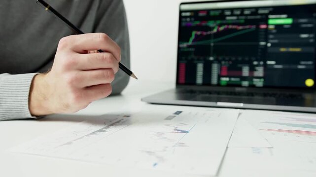 Business Analyst Studying Stock Market Financial Charts on Laptop