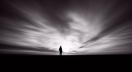 Fototapeta premium Solitude Concept with a Lone Person Standing Against a Dramatic Blurred Sky and Dark Horizon