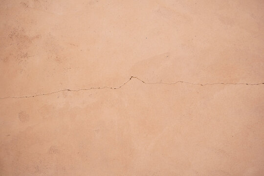 Terracotta wall texture with delicate crack, warm abstract background Description
