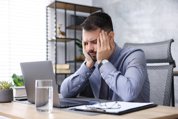 Naklejka premium Man feeling fatigue at wooden desk in office