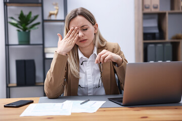 Obraz premium Woman feeling fatigue at wooden desk in office