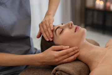 Beautiful woman receiving facial massage on couch indoors, closeup