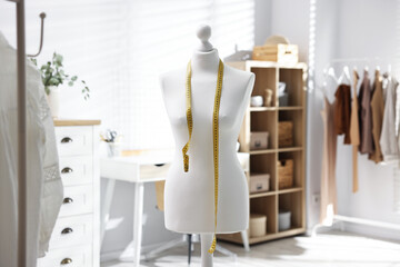Fototapeta premium Female mannequin with measuring tape in workshop
