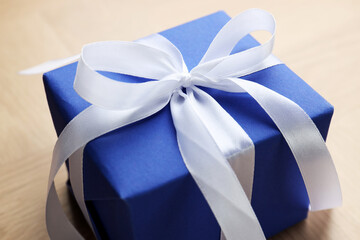 Beautiful gift box with bow on wooden table, closeup