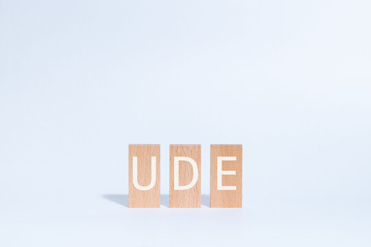 Eye-catching image of UDE text on wood blocks. The word stands for Undesirable Effect.