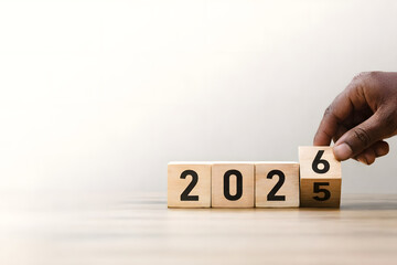 Naklejka premium The Year Ahead: A Hand Transitions into 2026: A person's hand turns the last block, marking the transition from 2025 to 2026, symbolizing anticipation, planning, and forward-thinking.