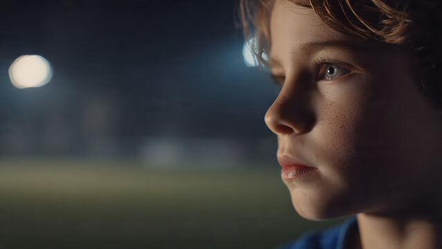 A young boy with a focused expression on his face at night