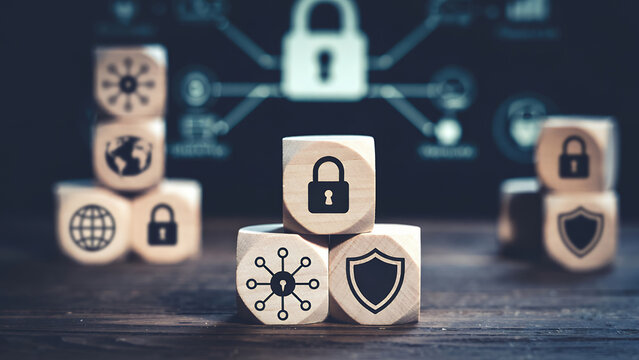 A focused shot of wooden cubes displaying security icons against a blurred tech background.