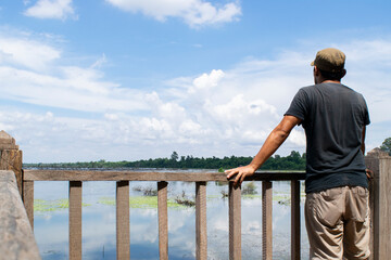 Obraz premium Man observing tranquil lake view in siem reap cambodia