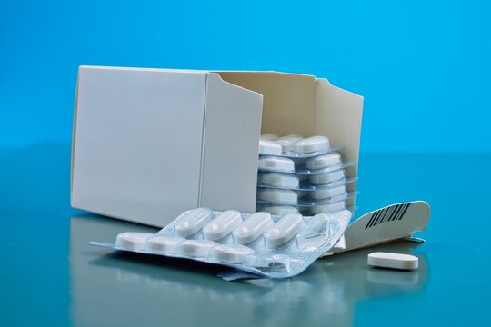 Medication White Pill And Aluminum Foil Packaging Blue Background