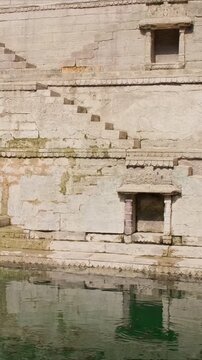 Water storage inside Toorji Ka Jhalra Baoli and stepwell - one of water sources in Jodhpur, Rajasthan, India. Sunny day, water ripples reflect walls of the pool. Camera horizontal pan