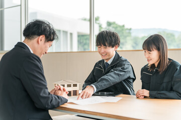 Fototapeta premium Male and female businessmen explaining and negotiating their own home to customers using house models and blueprints