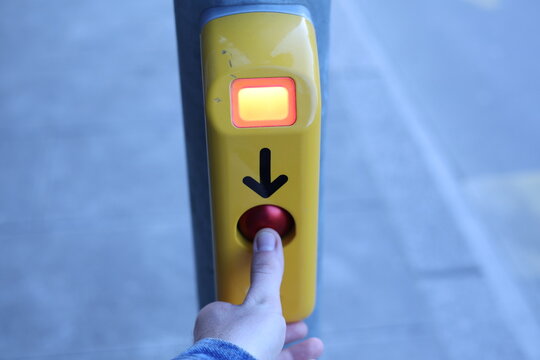 Activation d&rsquo;un bouton de passage pi&eacute;ton avec une main qui appuie sur le bouton pour traverser une rue en ville

