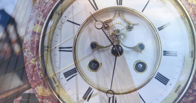Showing antique mantel clock sitting behind glass on mantel, with brass movement and marbled bezel