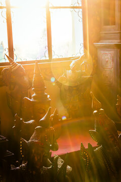 Traditional Asian statues bathed in warm golden sunlight with window lens flare